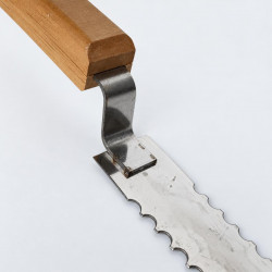 Close-up of the handle, curved bracket and serrated blade of a beekeeping knife
