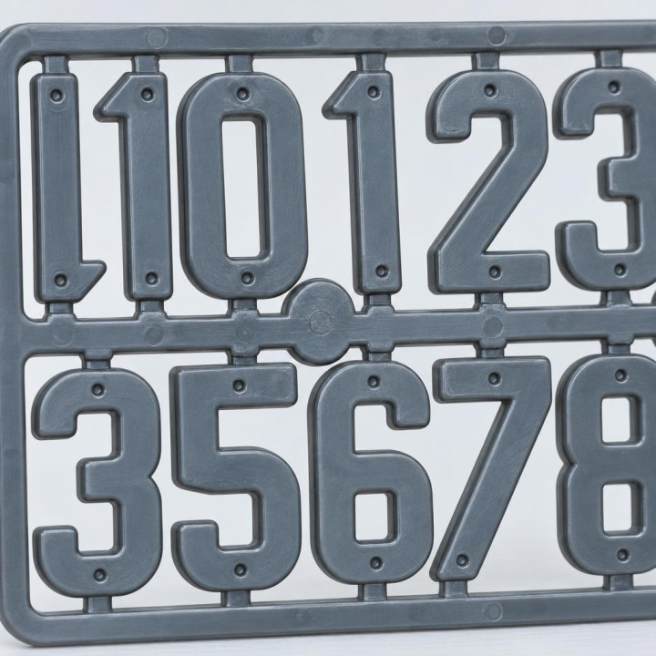 Close-up of gray plastic numbers in a frame with holes