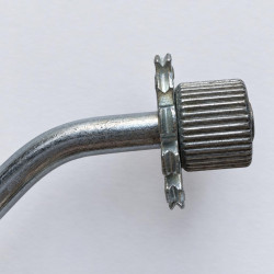 Close-up of ribbed roller and toothed disc on the bent metal shaft