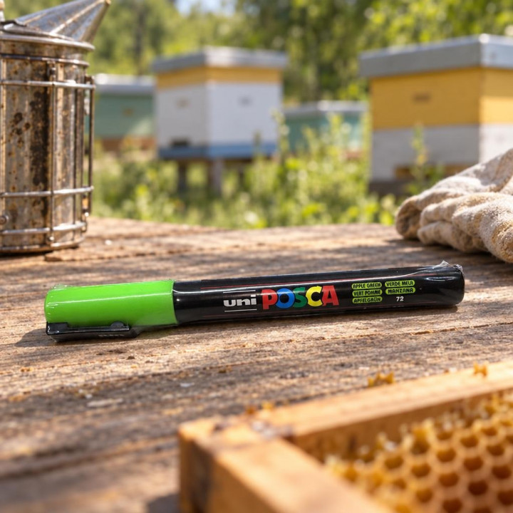 Маркер uni POSCA на дерев'яному столі пасіки, димар і вулики на тлі.