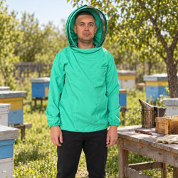 Man in beekeeping jacket with veil at an apiary near hives, table and smoker