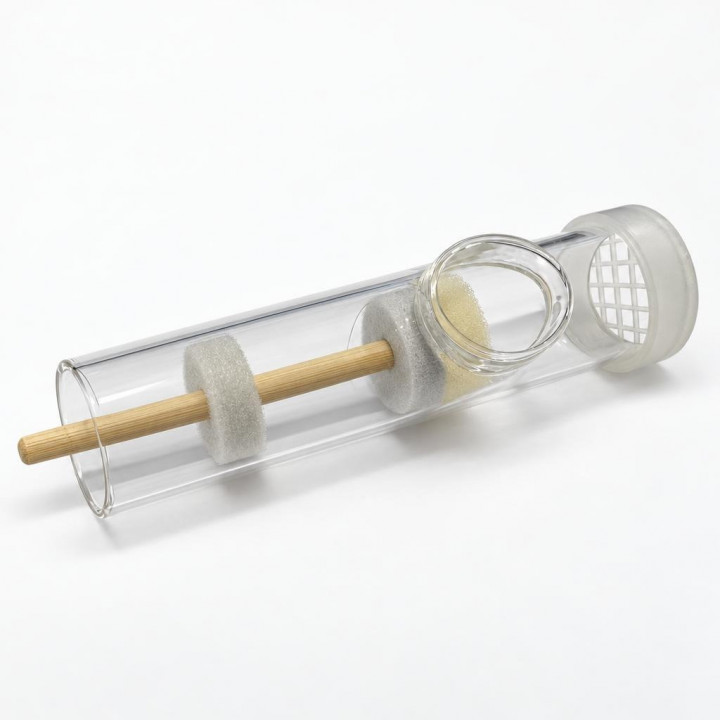 Queen marking tube side view on white background, showing plunger and mesh cap