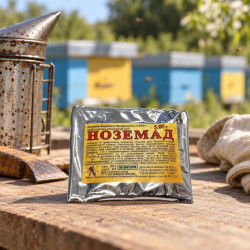 Nozemad 5 g SKIF packet on wooden table with smoker and glove at an apiary