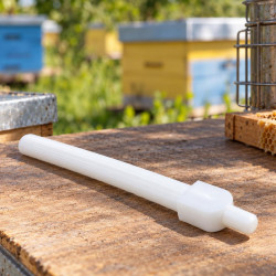 White cleaner on a wooden apiary surface, hives and smoker in the background