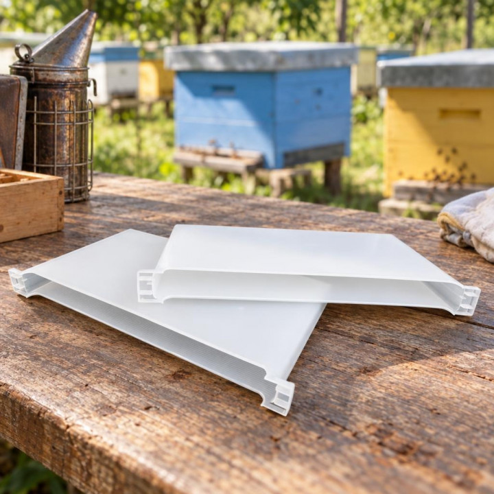 White plastic bee feeders on a wooden table by hives and a bee smoker